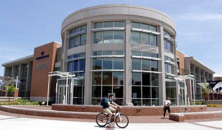 Student riding a bike in front of Broderick Dining Commons